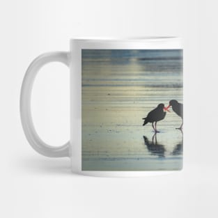 Two black oystercatchers silhouetted with orange beaks crossed, back-lit. Mug